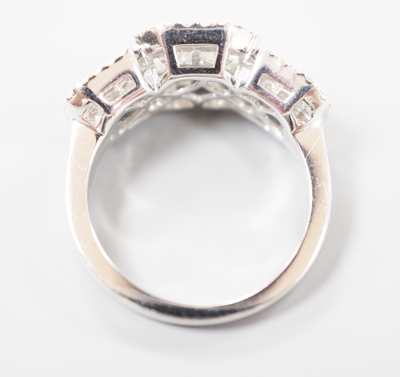 A modern 750 white metal, trapeze and round cut diamond set triple cluster dress ring, size M, gross weight 7 grams